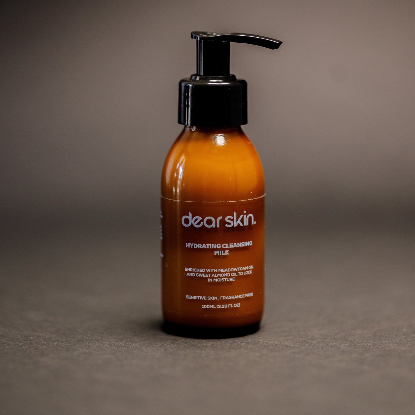 Dear Skin Hydrating Cleansing Milk in a 100ml amber pump bottle, formulated with meadowfoam and sweet almond oil to cleanse and moisturize sensitive skin.