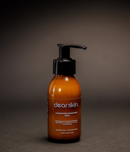Dear Skin Hydrating Cleansing Milk in a 100ml amber pump bottle, formulated with meadowfoam and sweet almond oil to cleanse and moisturize sensitive skin.