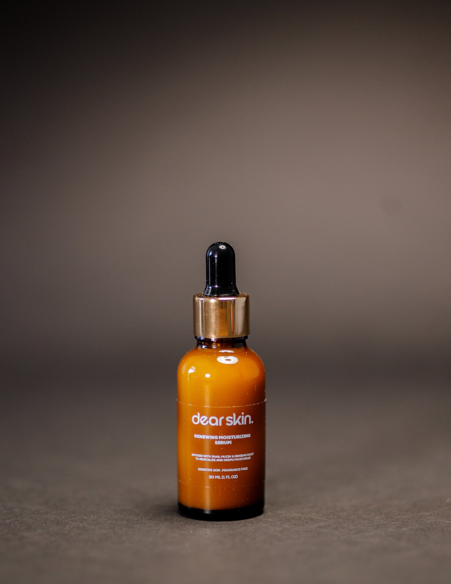 Dear Skin Renewing Moisturizing Serum in a 30ml amber bottle, infused with snail mucin and ginseng root to revitalize and hydrate sensitive skin