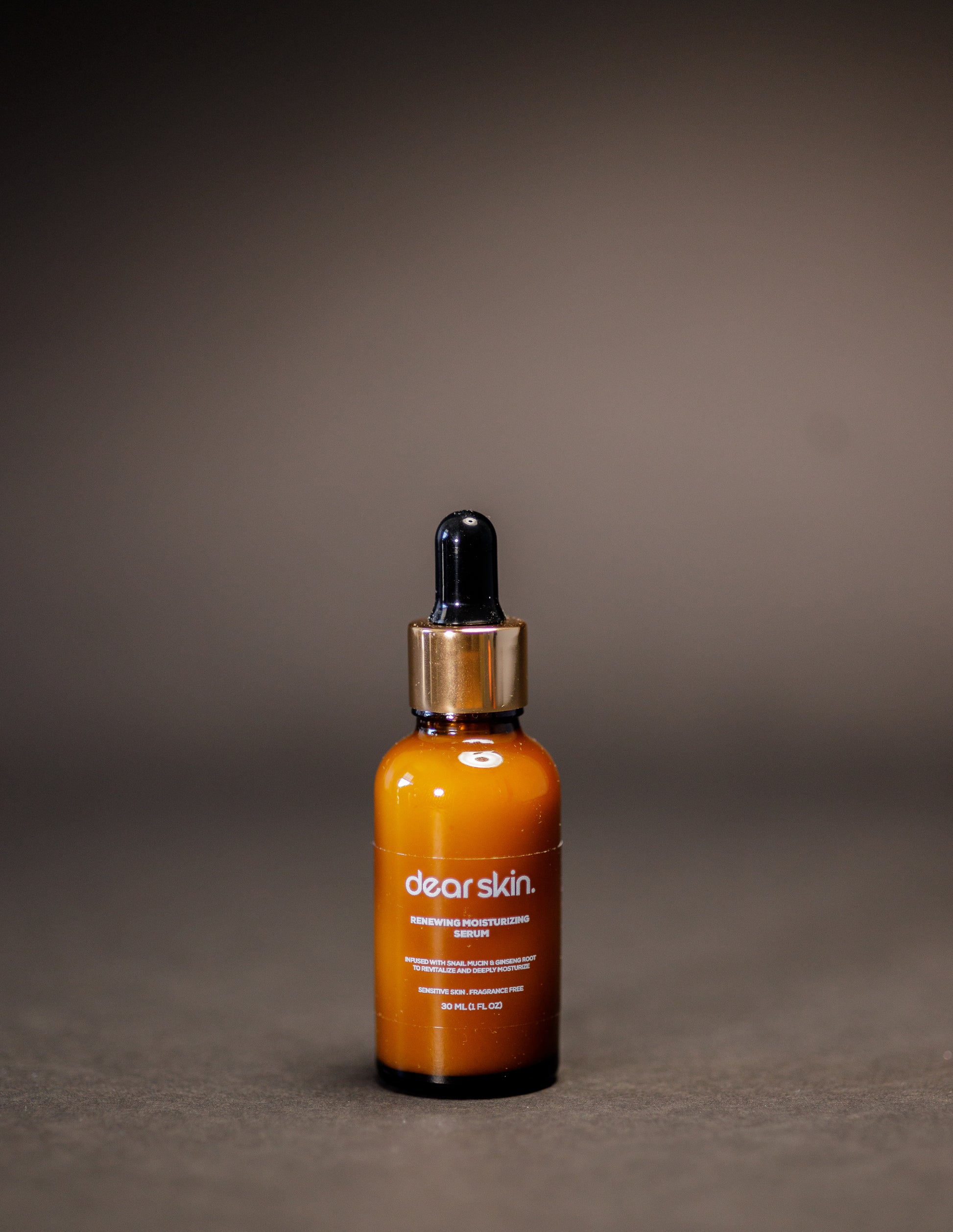 Dear Skin Renewing Moisturizing Serum in a 30ml amber bottle, infused with snail mucin and ginseng root to revitalize and hydrate sensitive skin